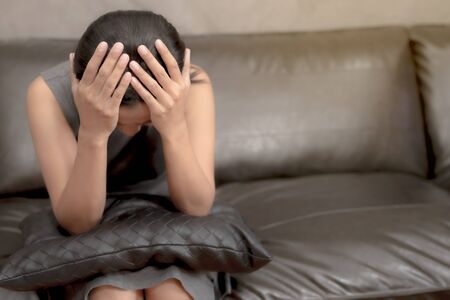 Women sit stressed.Sit on the sofa.She has a headacheThe concept of pressure, family hard work.の写真素材