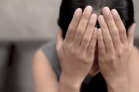 Women sit stressed.Sit on the sofa.She has a headacheThe concept of pressure, family hard work.の写真素材