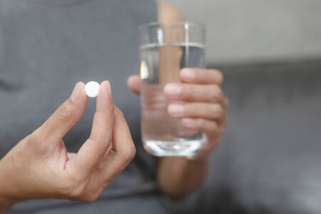 Close up of woman taking in pill she is pours the pills out of the bottle,taking painkiller to reduce sharp ache concept,health care and medicine concept.の写真素材