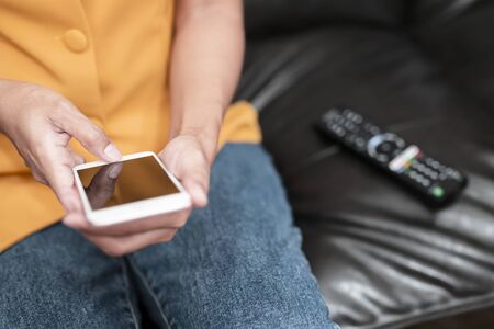 The hand is pressing the phone and remote control to select the channel by application in...