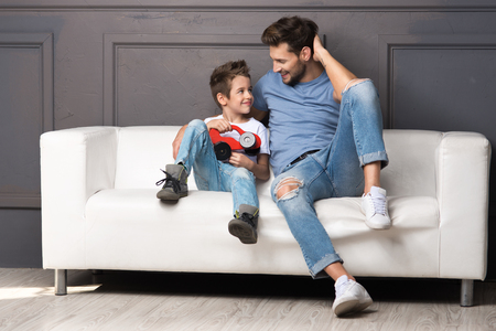 Father and son are sitting on the couchの写真素材