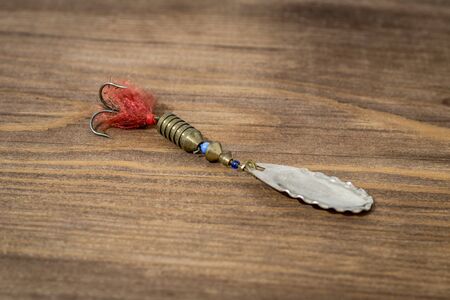 Spoon bait, lure, tackle, flies, wobbler for catching or fishing a predatory fish on deck wood backgroundの写真素材