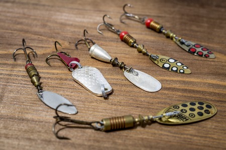 Spoon bait, lure, tackle, flies, wobbler for catching or fishing a predatory fish on deck wood backgroundの写真素材