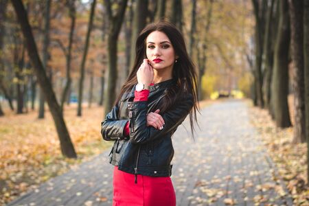 Autumn fashionable portrait of happy brunette young girl red lipstick outdoors in the cityの写真素材