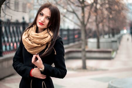 Autumn fashionable portrait of happy brunette young girl red lipstick outdoors in the cityの写真素材