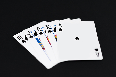 Royal Flush of spades in poker cards game on a black background.
