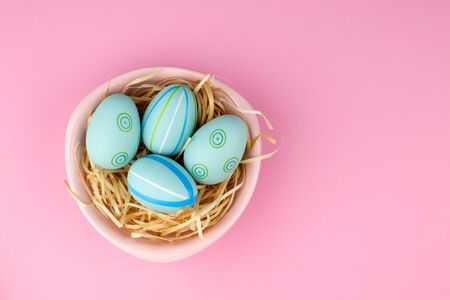 Happy easter composition. Nest with blue pained easter eggs. Texture pink background. Flat lay, top view and copyspace.の写真素材