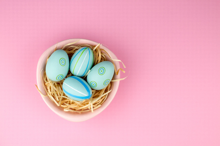 Happy easter composition. Nest with blue pained easter eggs. Texture pink background. Flat lay, top view and copyspace.の写真素材