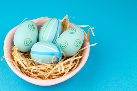 Happy easter composition. Nest with blue pained easter eggs. Texture blue background. Flat lay, top view and copyspace.の写真素材