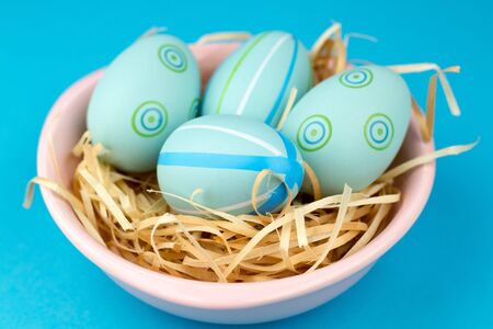Happy easter composition. Nest with blue pained easter eggs. Texture blue background. Flat lay, top view and copyspace.の写真素材