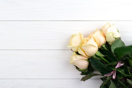 Bouquet of beige roses on white wooden vintage background, flat lay, top view, copy space. Mothers day. Valentines day.の写真素材