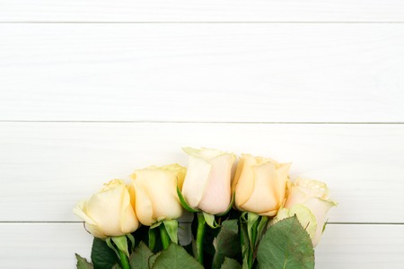 Bouquet of beige roses on white wooden vintage background, flat lay, top view, copy space. Mothers day. Valentines day.の写真素材