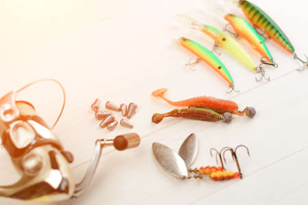 Fishing rod with reel, spoon baits, tackles and wobblers in box for catching or fishing a predatory fish on white vintage wooden background.の写真素材