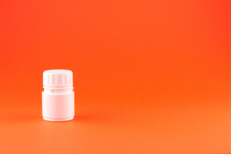 Close up white pill bottle on orange background with copy space.の写真素材