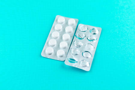 Full and empty packs of white pills packed in blisters with copy space on turquoise background.の写真素材