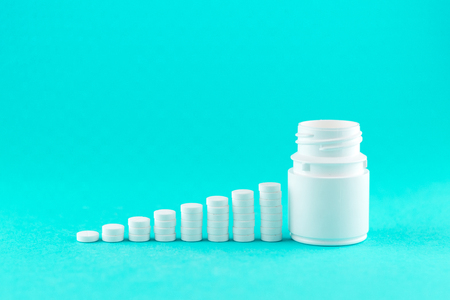 Close up pyramid concept of white pills and bottle on turquoise background with copy space.の写真素材