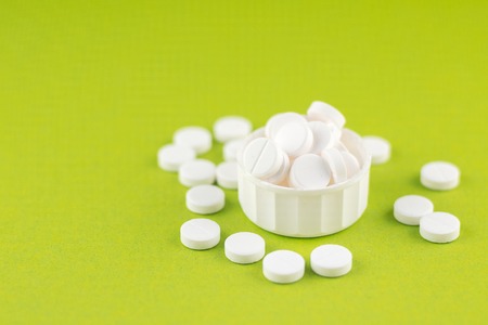 Close up white pills and capsules in cap on pear yellow background with copy spaceの写真素材
