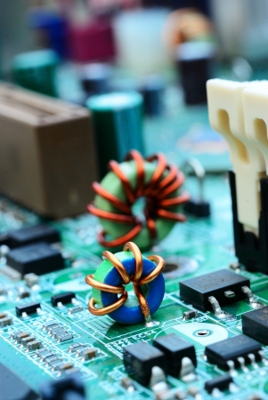 Close up of an mini electronic printed ferrite ring with computer mainboard backgroundの写真素材