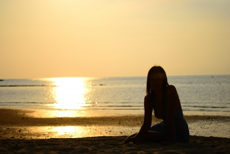 Silhouette of Asian woman sit on the beachの写真素材