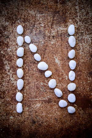 Alphabet made form white stone on rustry floor background.の写真素材