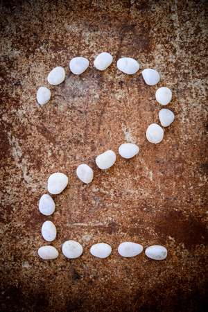 Number alphabet made form white stone on rustry floor background.の写真素材