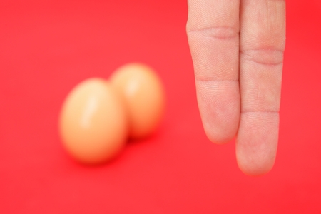 Two finger and egg on isolated red backgroundの写真素材