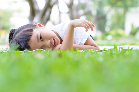 Asian kid portrait with relax pose in the green gardenの写真素材