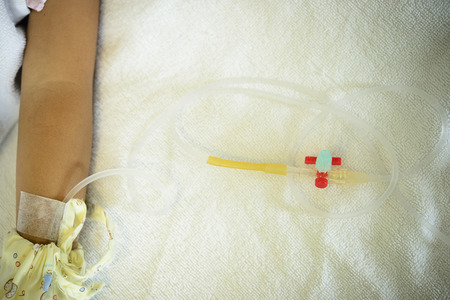 Saline solution tube with patient arm on bedの写真素材