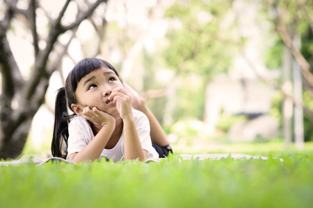 Asian kid thinking while playing in the gardenの写真素材