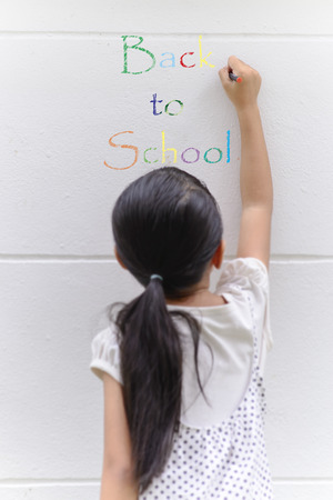 Kid writing on wall with her black pencilの写真素材