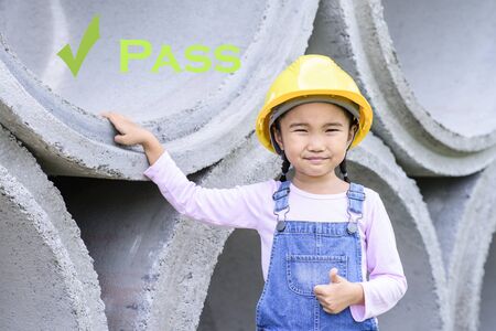 Kid civil engineer inspecting huge concrete pipe and make a thumb up for show passの写真素材