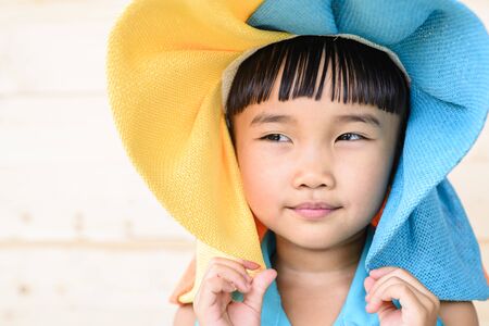 Little girl put the hat on her head with wood backgroundの写真素材