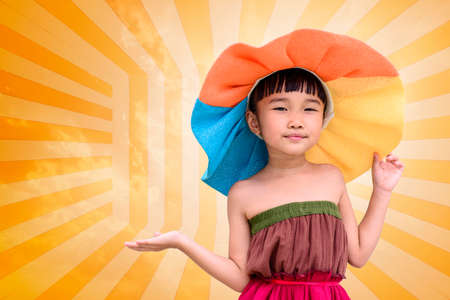 Little girl with summer fashion dress and hat on orange backgroundの写真素材
