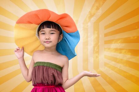Little girl with summer fashion dress and hat on orange backgroundの写真素材