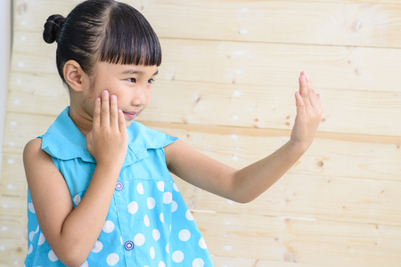 Little girl Check herself with blur wood backgroundの写真素材