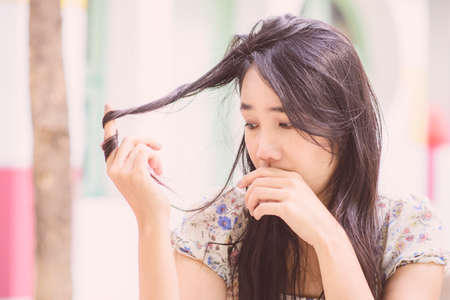 Asian woman thinking; Vintage tone; Sad mood; Hair health checkingの写真素材