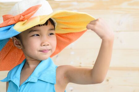 Little girl pose with hat and blur wood backgroundの写真素材