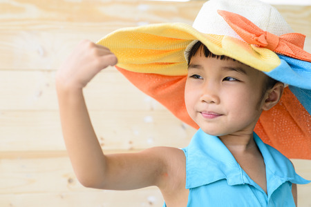 Little girl pose with hat and blur wood backgroundの写真素材