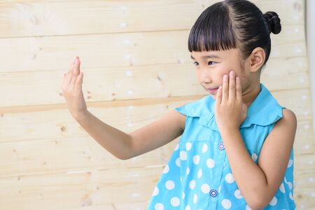 Little girl Check herself with blur wood backgroundの写真素材