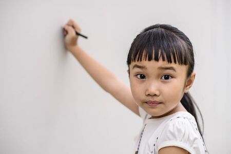 Kid with surprise mood while writing on wallの写真素材