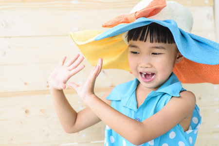 Little girl pose with the hat on her head and blur wood backgroundの写真素材