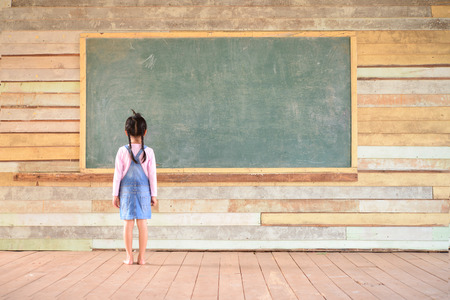 Little girl look at blank green blackboardの写真素材