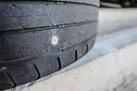 close up of screw nail puncturing car tire