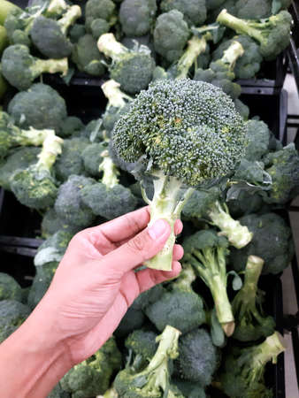 Left-hand picks broccoli from a tray that is sold in the market, broccoli sent from the garden to the consumer.の写真素材