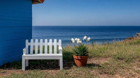 White bench in front of a blue house with the sea in the backgroundの素材