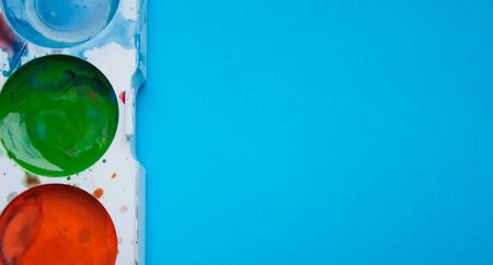 multicolored paints on a blue background
