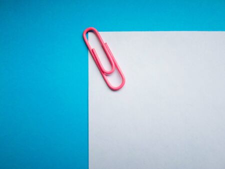 Two colored papers with blue and white flowers. White and blue paper in the middle of the horizontal line, on a white paper pink clip. backgroundの写真素材
