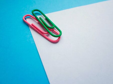 Two colored papers with blue and white flowers. White and blue paper in the middle of the horizontal line, on a white paper pink and green clip. backgroundの写真素材