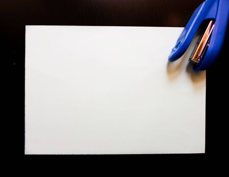 blue stapler and white paper on a black table. place to write. stationery. education conceptの写真素材