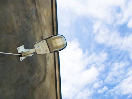 street lamp against the sky is attached to a concrete wall. electric lamp